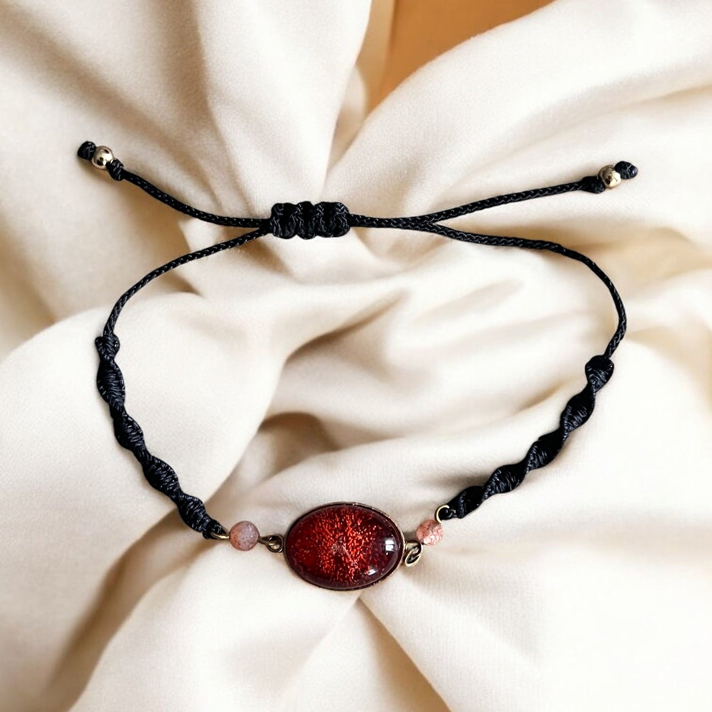 Bracelet en macramé noir, résine rouge et pierre de soleil – “Rouge Soleil”