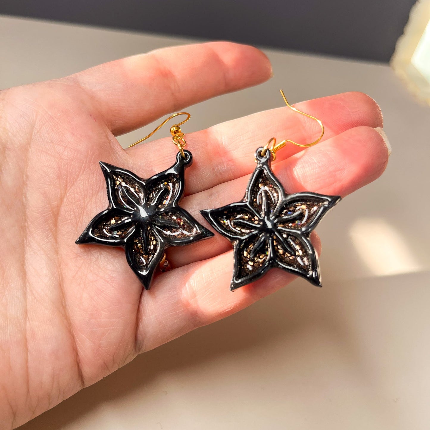 Boucles d’oreilles fleur étoilée en acrylique noir et résine cuivrée pailletée – Étoile assumée